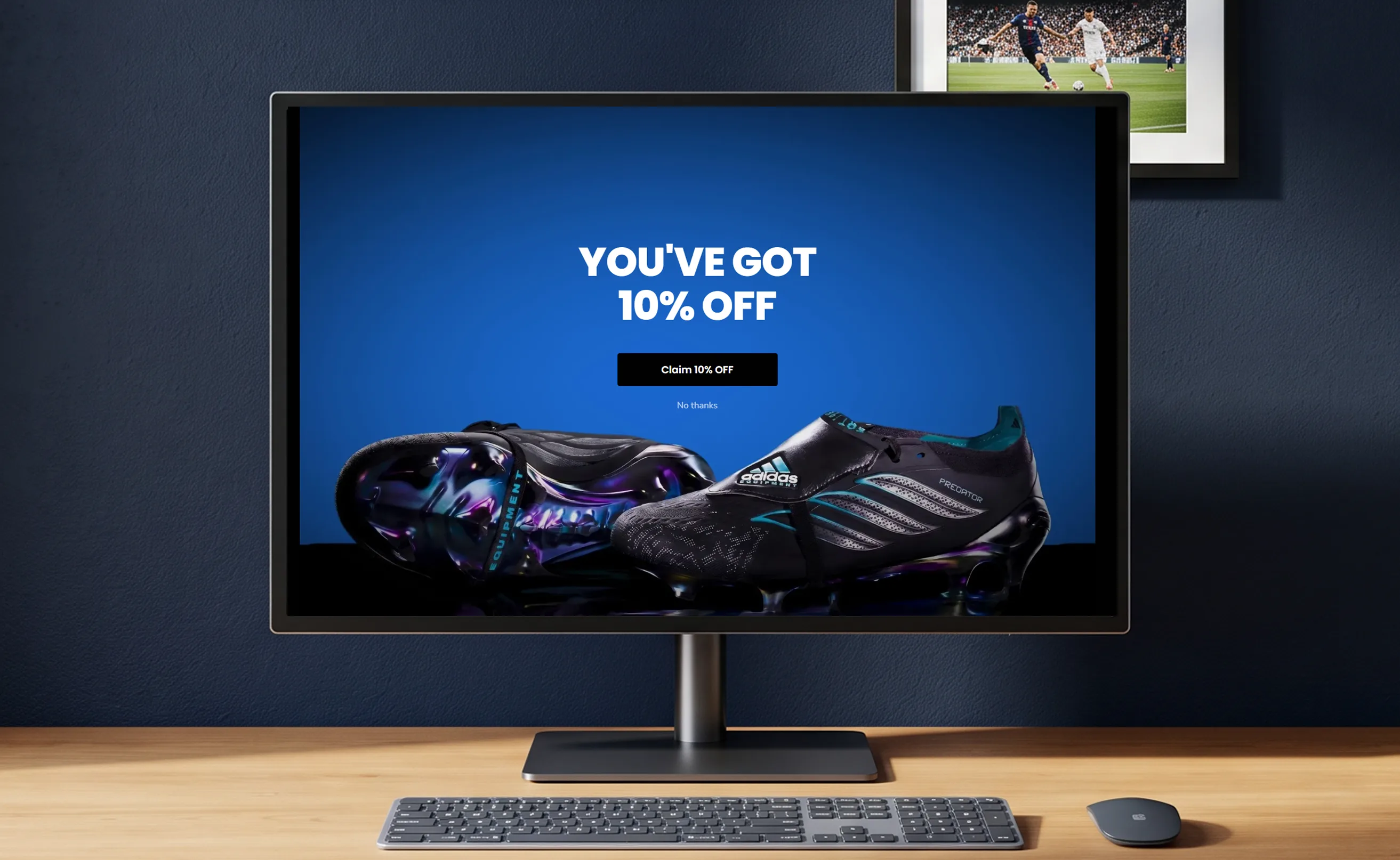 Soccer Wearhouse &ldquo;You&rsquo;ve got 10% off&rdquo; discount pop-up shown on a monitor on a desk, featuring Adidas Predator cleats.